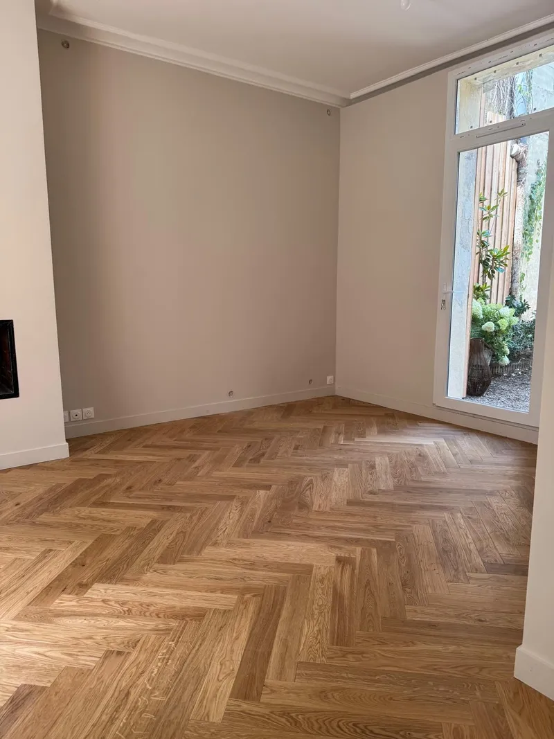 Aménagement intérieur d’un salon avec bibliothèque murale sur mesure, cheminée noire et mobilier contemporain