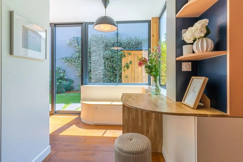 Chambre lumineuse avec tête de lit capitonnée, mobilier noir et textiles gris