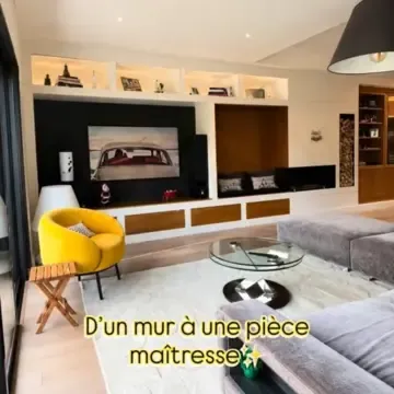 Aménagement intérieur d’un salon avec bibliothèque murale sur mesure, cheminée noire et mobilier contemporain