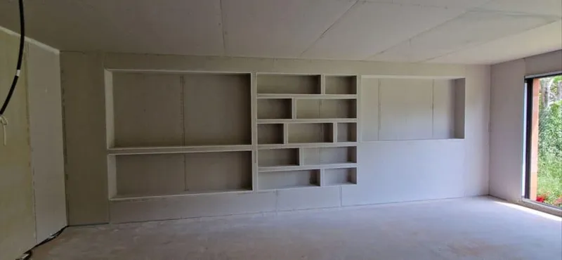 Bibliothèque murale en plaques de plâtre en cours de réalisation dans une pièce vide
