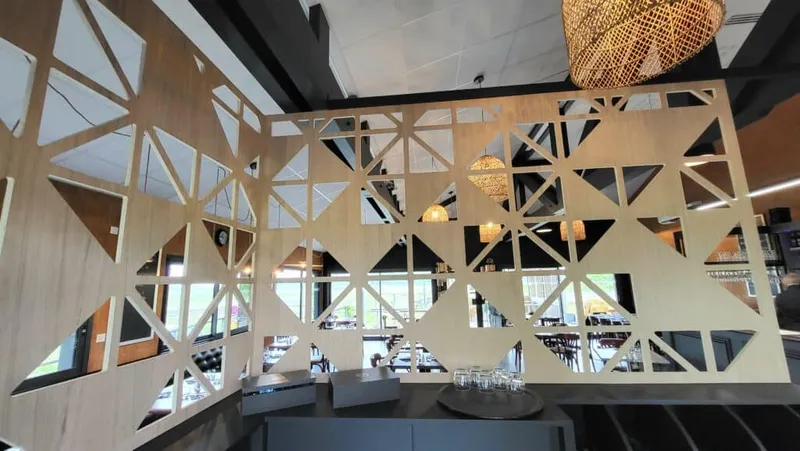 Claustra en bois ajouré séparant les espaces d’un restaurant contemporain