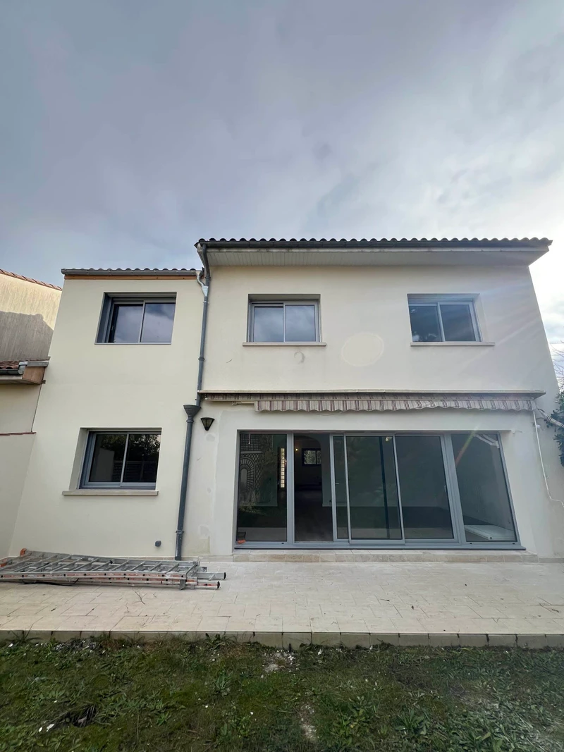 Façade de maison claire avec grande baie coulissante en aluminium