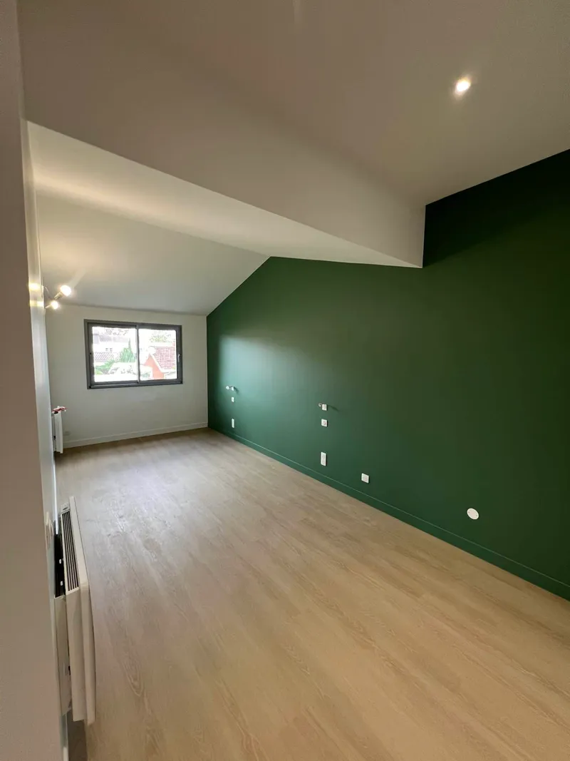 Chambre rénovée sous pente avec mur vert profond et sol aspect bois