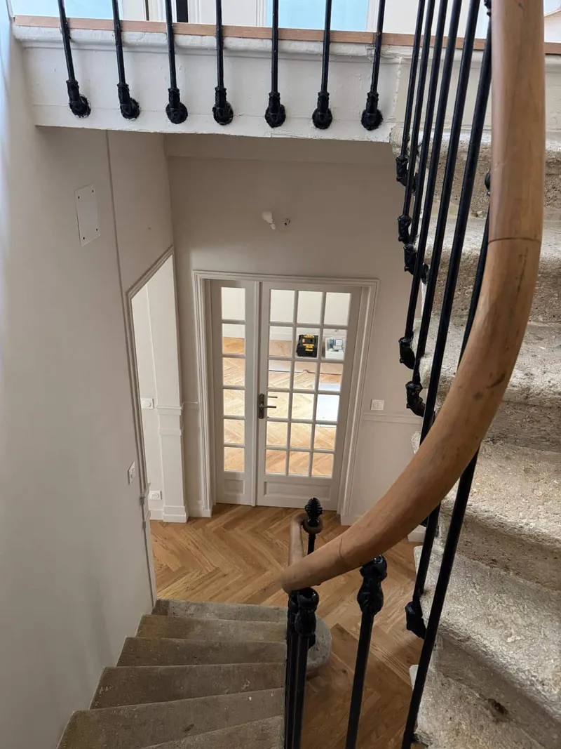 Escalier en pierre avec garde-corps en fer forgé et palier en parquet à chevrons