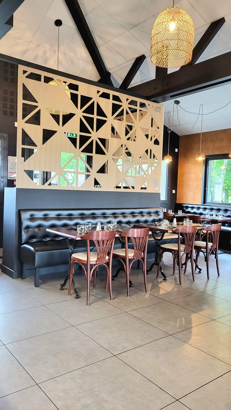 Restaurant contemporain avec banquettes en cuir, claustra en bois et tables dressées