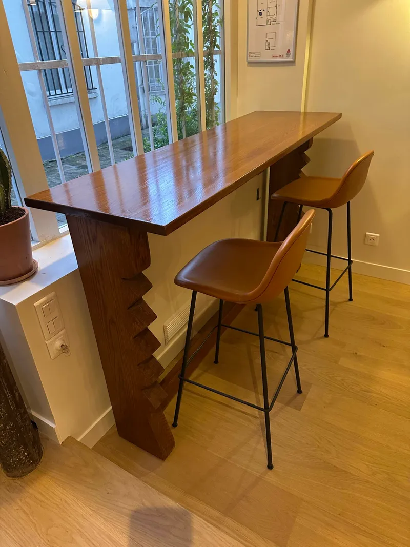 Comptoir en bois sculpté et tabourets en cuir dans un intérieur lumineux