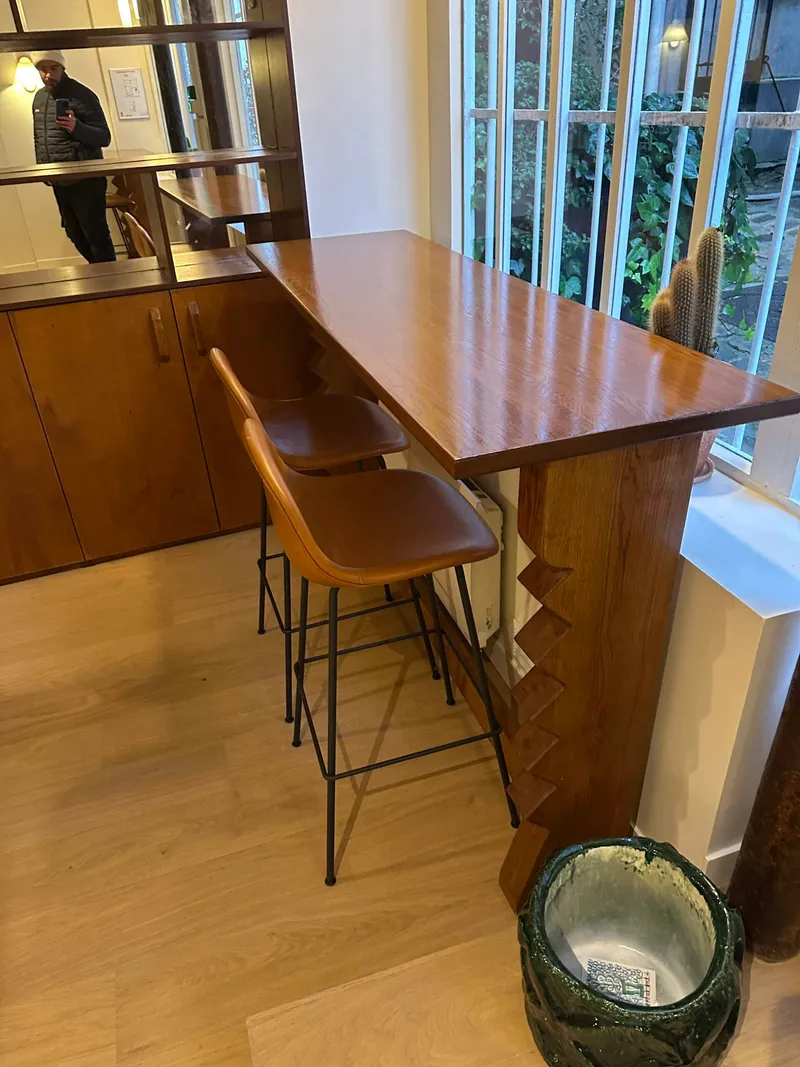 Comptoir bar en bois avec deux tabourets en cuir devant une grande fenêtre
